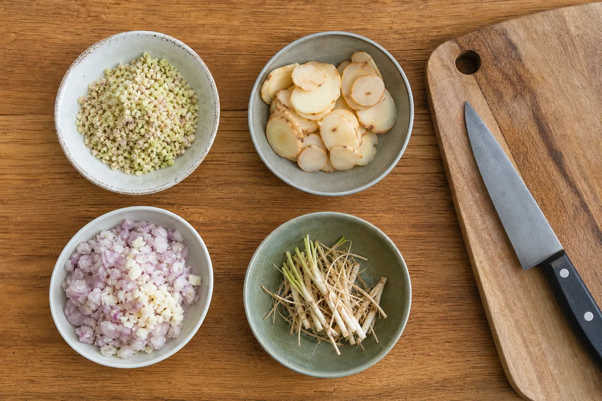 Aromates émincés séparément dans des petits bols avant le pilage d&rsquo;une pâte de curry